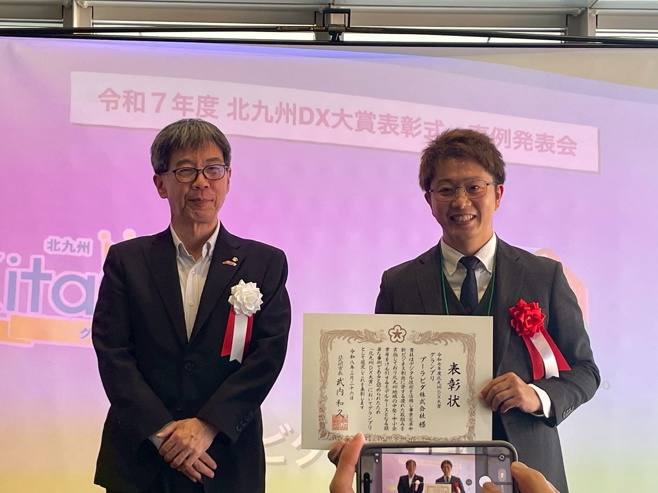 令和7年度 北九州DX大賞 グランプリの表彰式で賞状を持つ様子